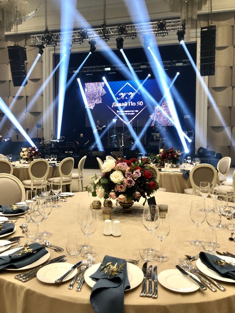 Gala dinner table setup with stage lighting and floral centerpieces