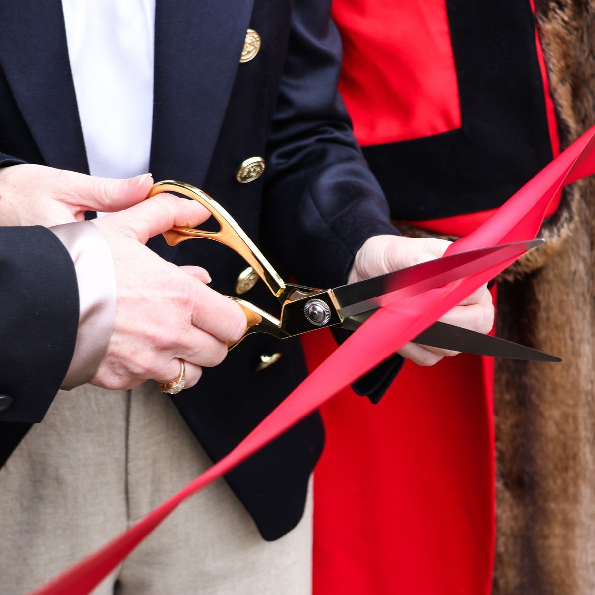 Close-up of a red ribbon-cutting ceremony with gold scissors